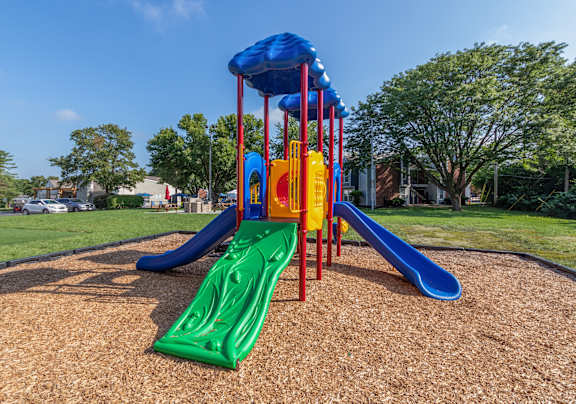 A playground with a blue, green, and yellow slide.
