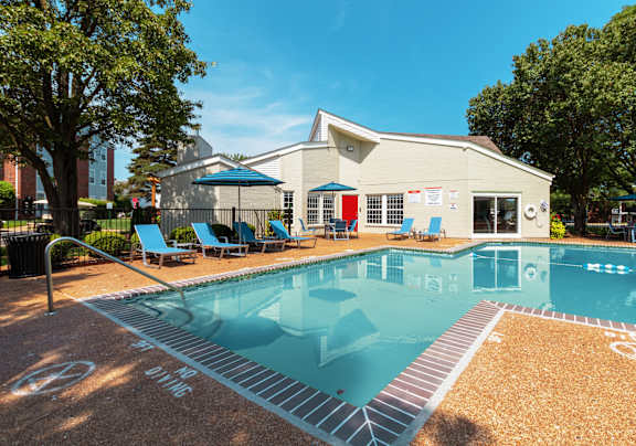 A swimming pool with a diving board and a building in the background.