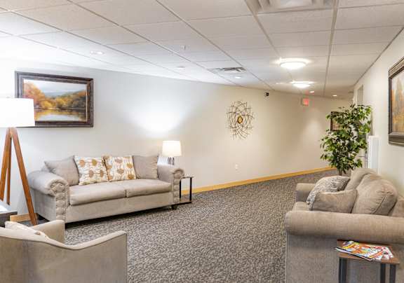 a living room with couches and chairs and a painting on the wall