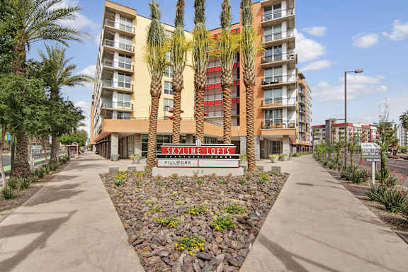 an empty sidewalk in front of a building with palm trees