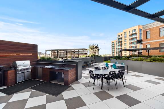 A black and white checkered patio with a barbecue grill and chairs.