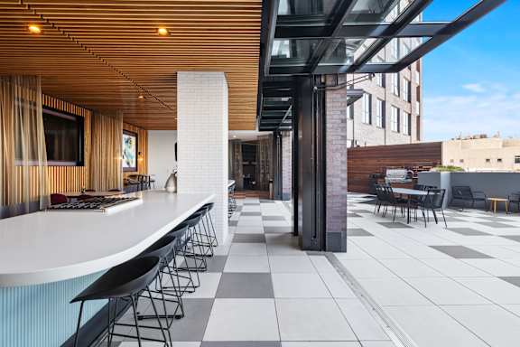A modern bar area with black and white tiled floors and a curved white counter.