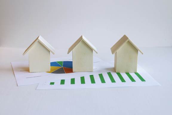 Three small houses are on display with a chart and graph in front of them.