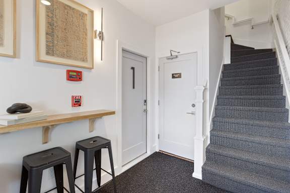 A hallway with a staircase and a white door.
