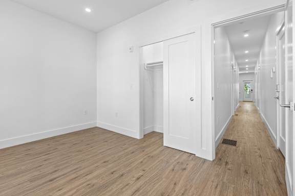 A long hallway with white doors and wooden floors.