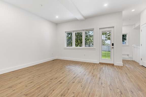 A room with wooden flooring and white walls.