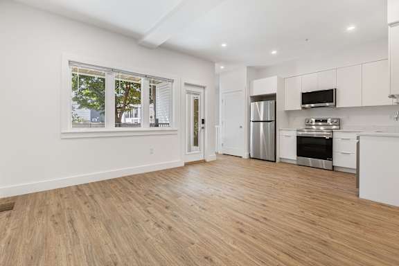 A kitchen with white cabinets and a wooden floor.