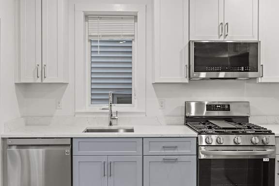 A modern kitchen with a stove, sink, and cabinets.