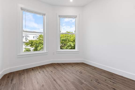 A room with two windows overlooking a green landscape.