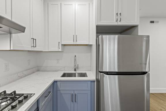 A modern kitchen with a stainless steel refrigerator and blue cabinets.