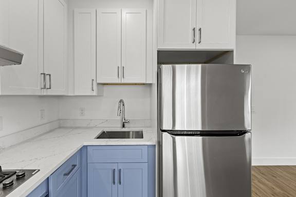 A modern kitchen with a stainless steel refrigerator and blue cabinets.