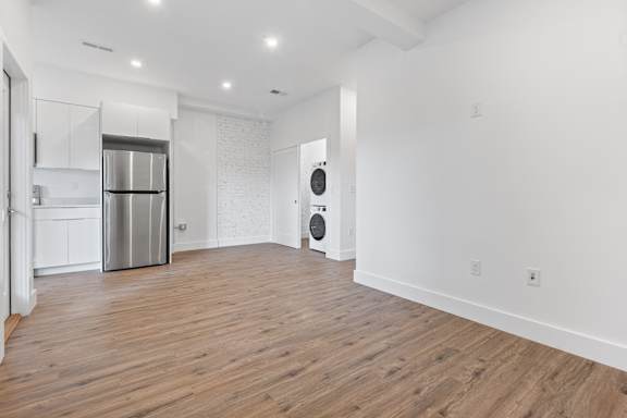 A spacious kitchen with white walls and wooden flooring.