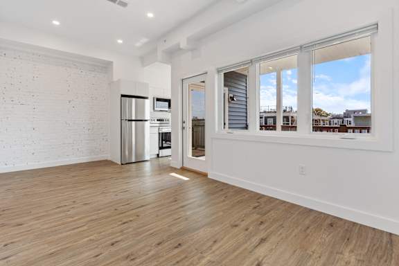 A spacious room with wooden floors and a white brick wall.