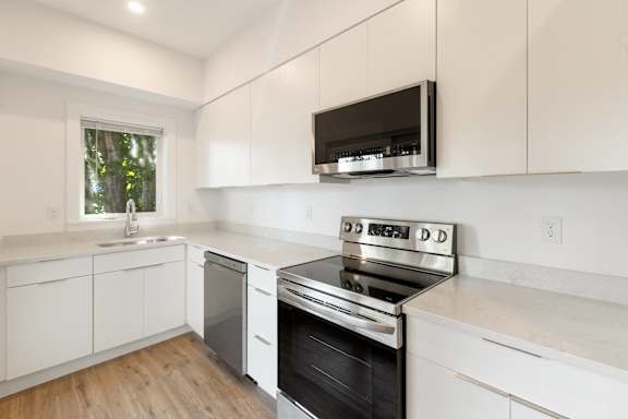 A modern kitchen with white cabinets and a black stove top oven.