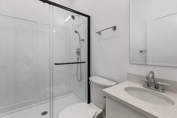 A white bathroom with a walk in shower and toilet.