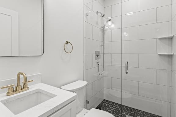 A white bathroom with a marble sink and a toilet.
