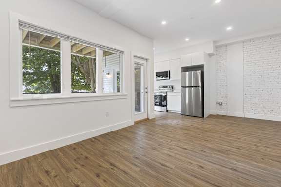 A kitchen with white walls and wooden floors.