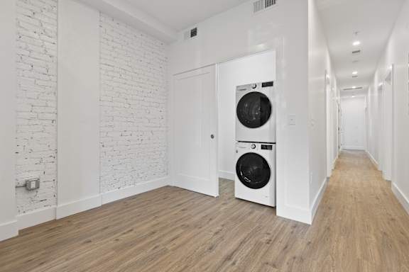 A white brick wall with a washing machine in the corner.