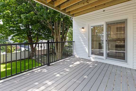 A white house with a deck and a black fence.