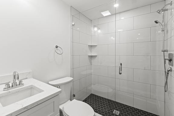 A white bathroom with a toilet, sink, and shower.