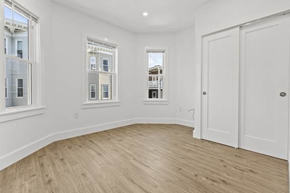 A room with white walls and wooden flooring with a white door.