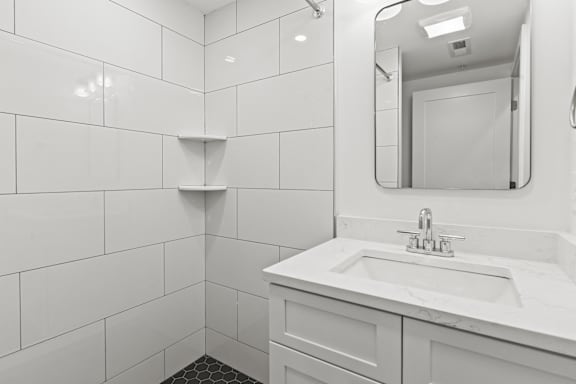 A white bathroom with a sink and mirror.