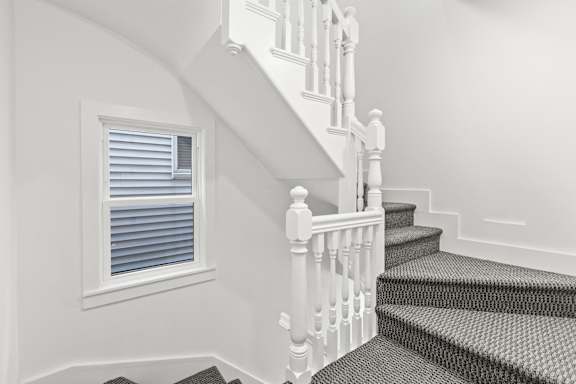 A staircase with a window and a white railing.