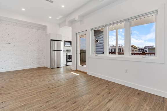 A spacious room with wooden floors and a white brick wall.