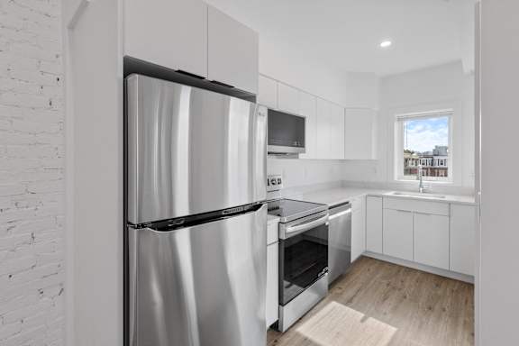 A modern kitchen with a stainless steel refrigerator and oven.