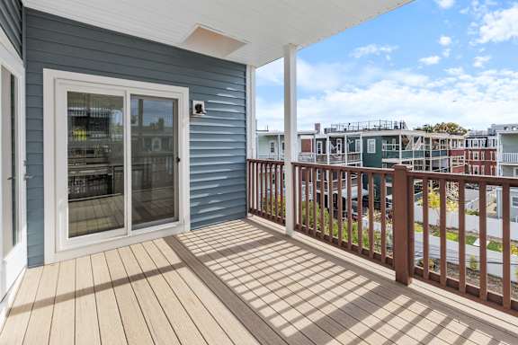 A balcony with a sliding glass door and a wooden floor.