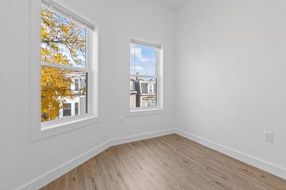 A room with a window showing a view of a building and trees.