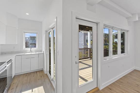 A white interior of a house with a deck outside.
