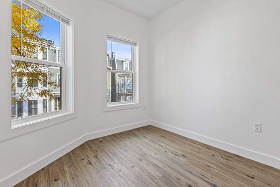 A room with a window showing a view of a building and trees.