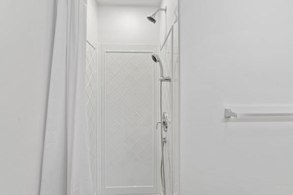 A white bathroom with a shower and a door.
