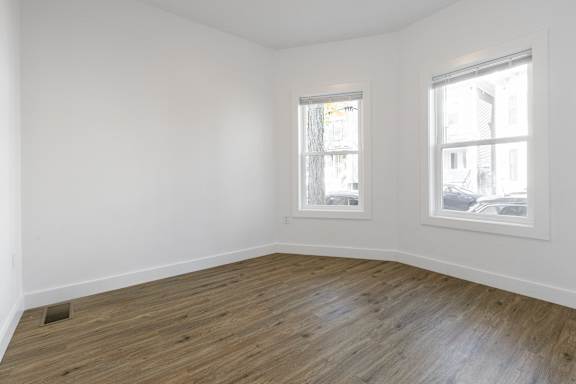 A room with wooden floors and two windows.