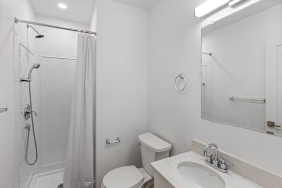 A white bathroom with a toilet, sink, and shower.