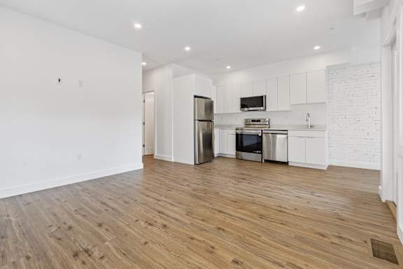 A kitchen with white cabinets and a wooden floor.
