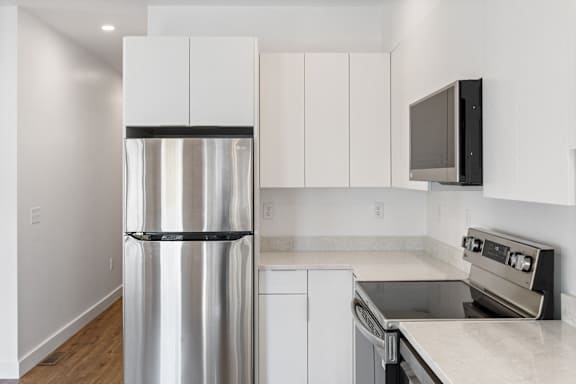 A modern kitchen with a stainless steel refrigerator and white cabinets.