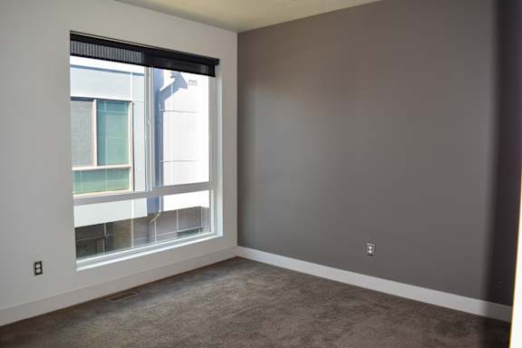 A room with a large window and a view of a building outside.