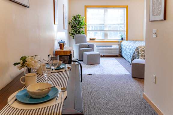 a living room with a dining table and a bedroom with a bed