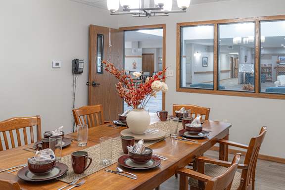 a dining room with a wooden table and chairs and a vase with flowers