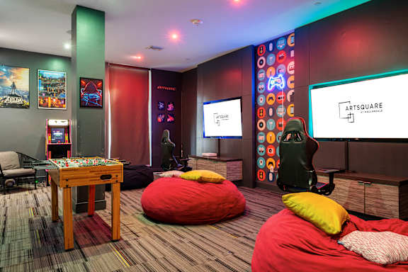 A room with a bean bag chair and a table with a game console on it.