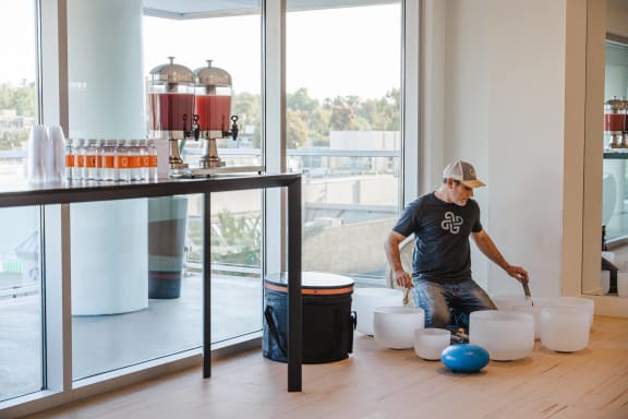 a man kneeling on the floor stirring buckets in a room