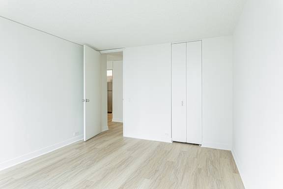 A white room with a wooden floor and a white door.