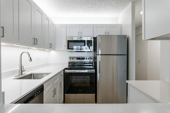 A modern kitchen with stainless steel appliances and white cabinetry.