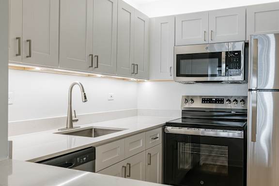 A modern kitchen with a stainless steel refrigerator, oven, and microwave.
