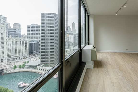 A room with a large window overlooking a river and city buildings.
