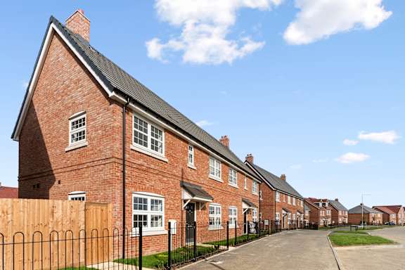 A row of red brick houses with a black fence in front.