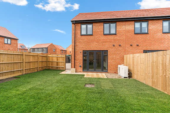 A red brick house with a green lawn in front.