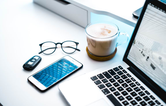 Laptop, phone, glasses and coffee on white table